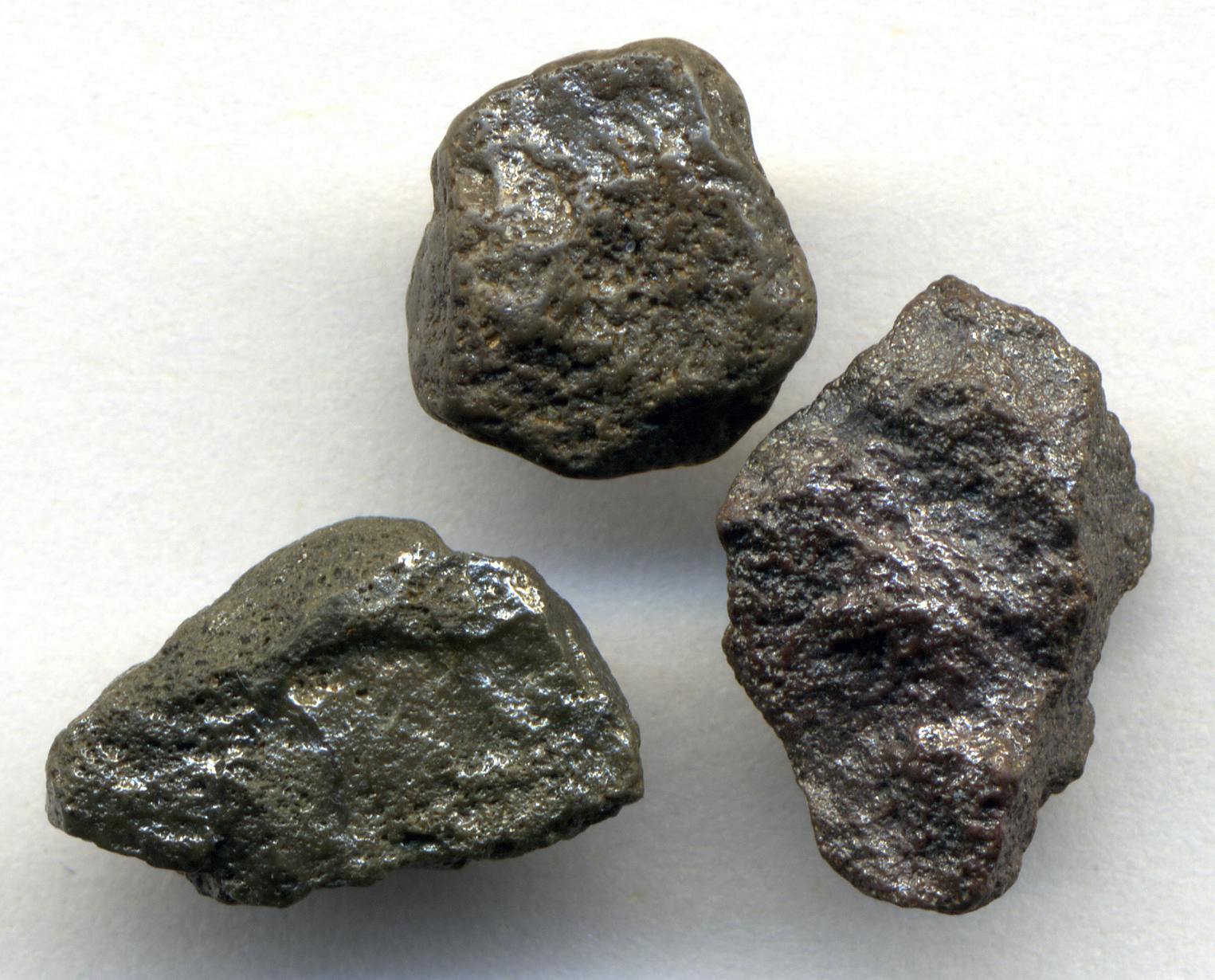 three lumpy and pox-marked black rocks